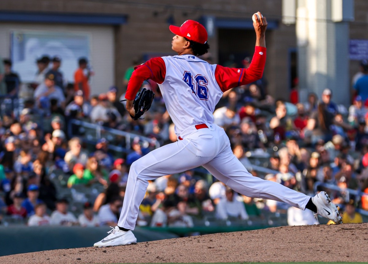 Baseball pitcher in a white and red uniform delivering a pitch on the mound with a crowded stadium in the background