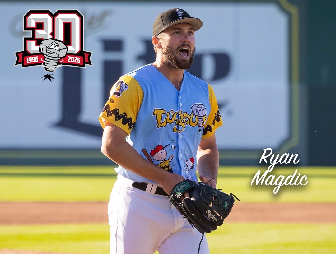 Baseball pitcher Ryan Magdic in a blue-and-yellow uniform on the mound, gloves ready for action.