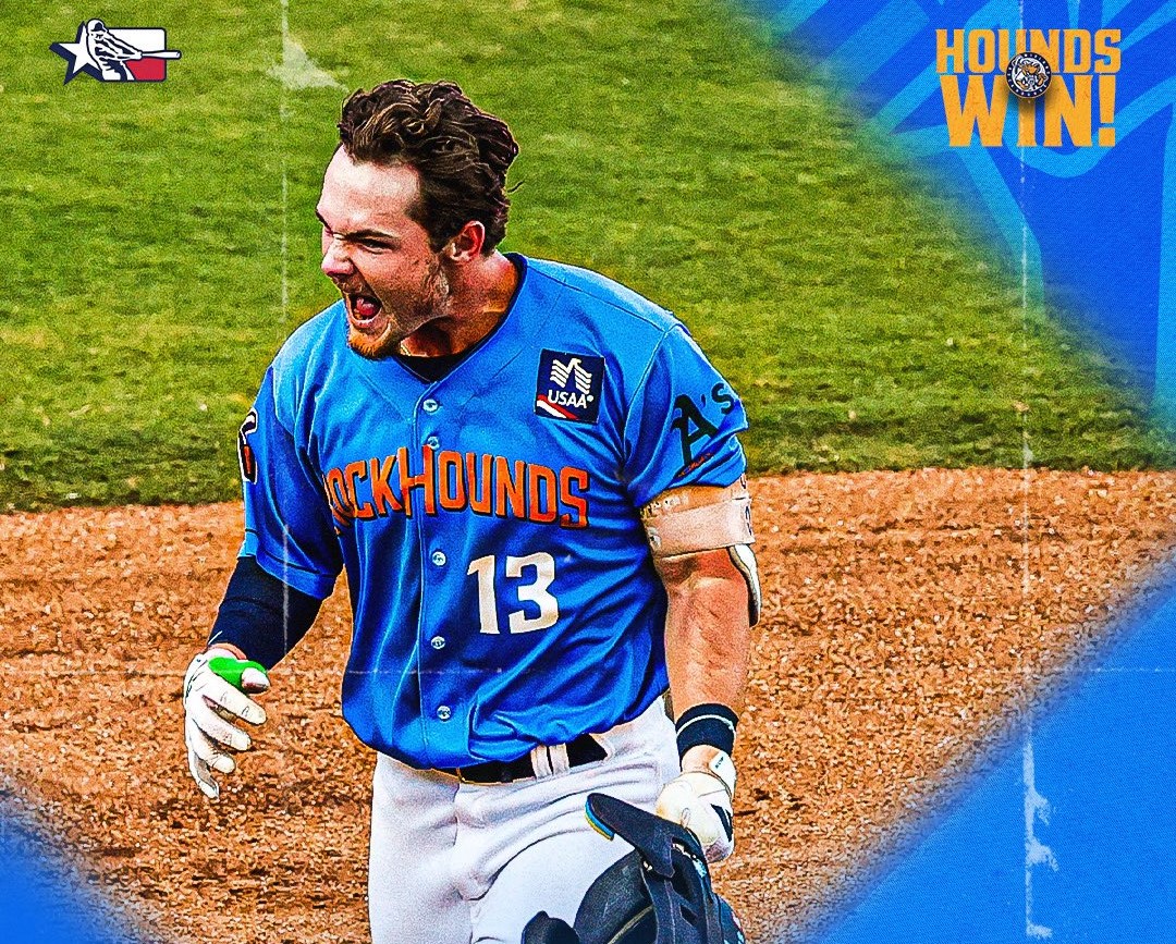 Baseball player in blue RockHounds jersey (#13) celebrating on a dirt infield with grass behind him.